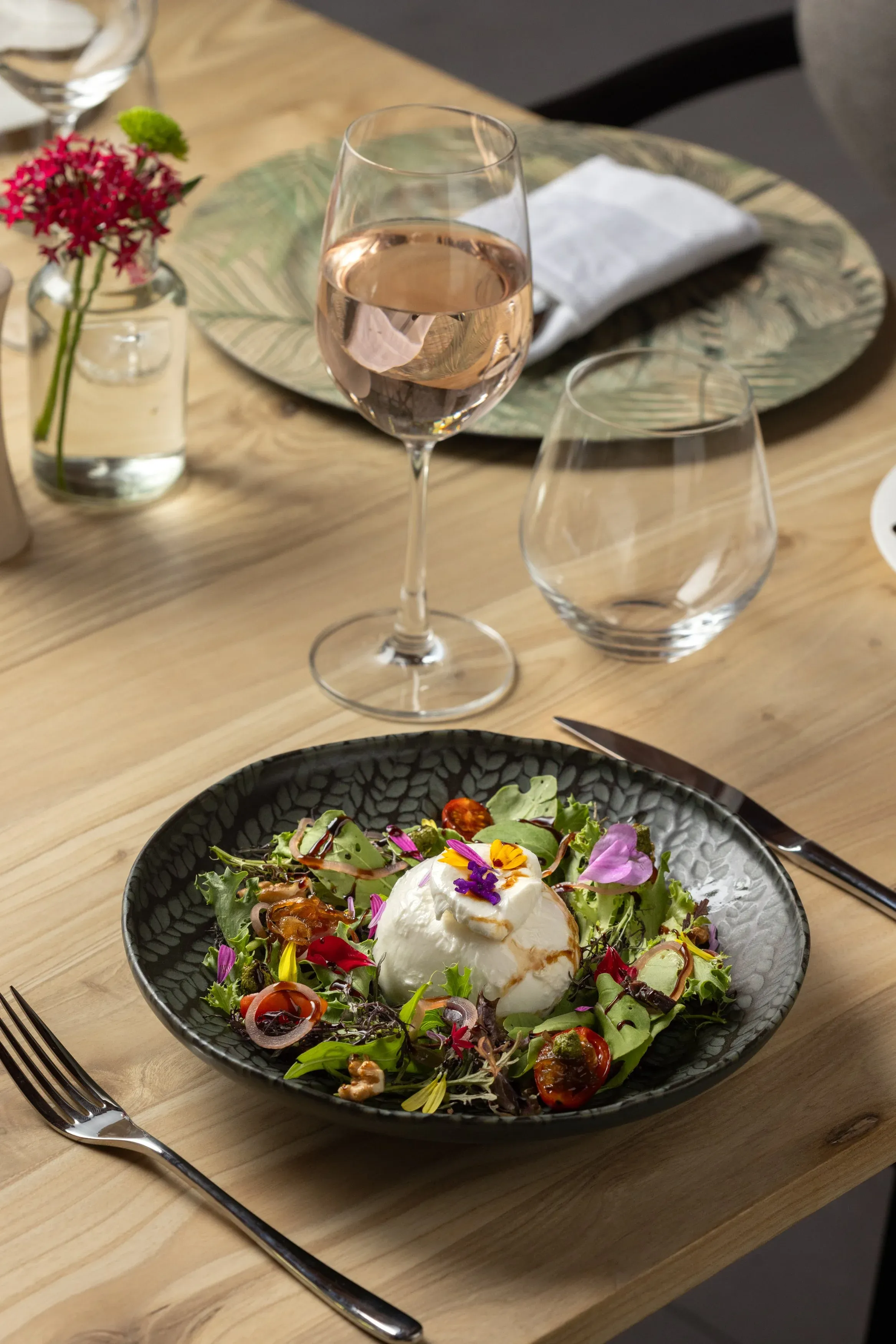 Burrata salad with edible flowers, served with a glass of rosé