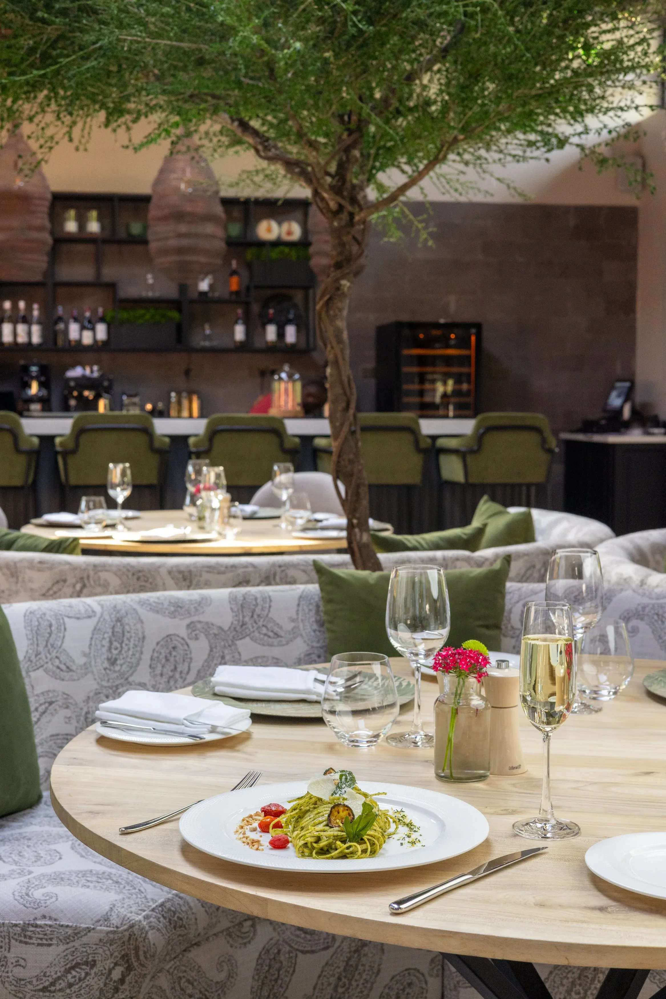 The Royal 58 dining room with an indoor tree, green booths and laid tables