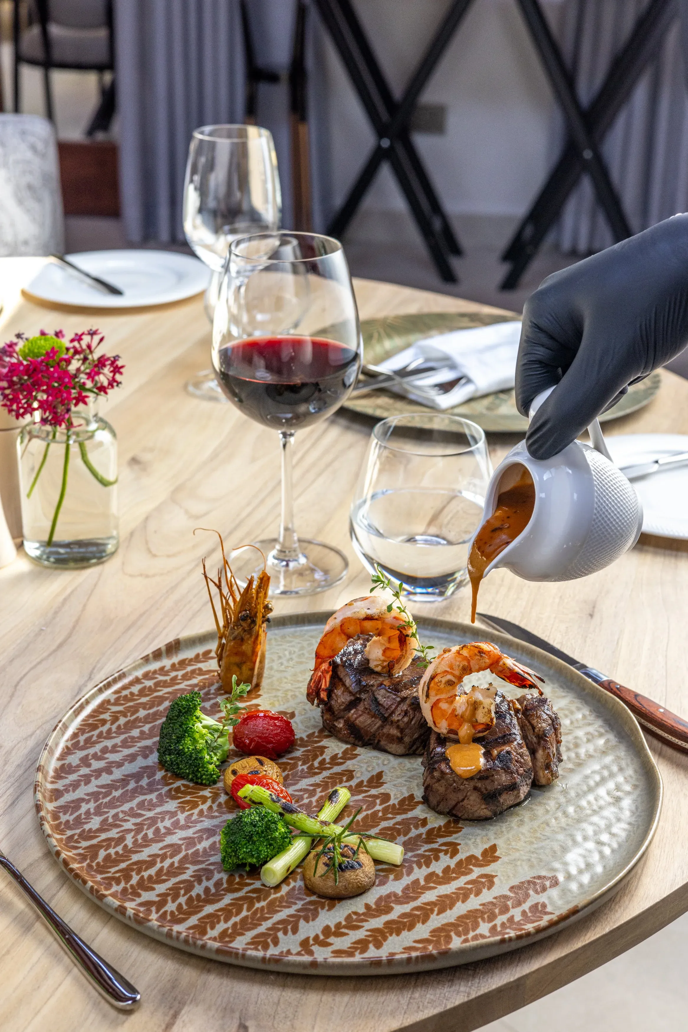 A server pouring sauce over surf and turf at the table
