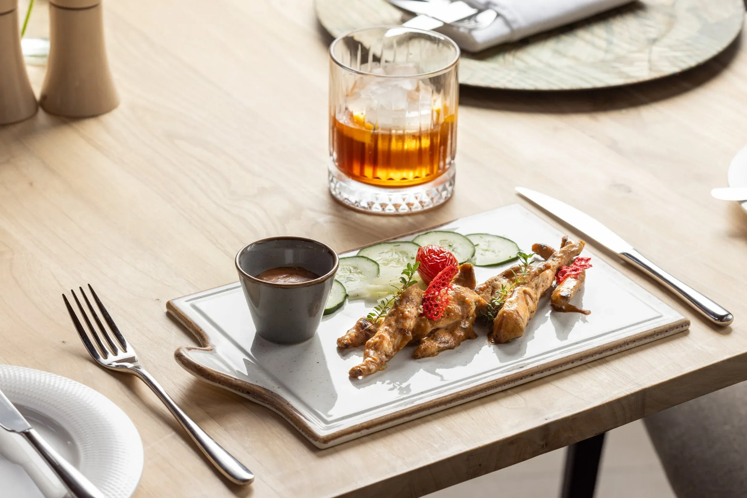 Skewered starter with cucumber and a dipping sauce, served with a whisky on ice