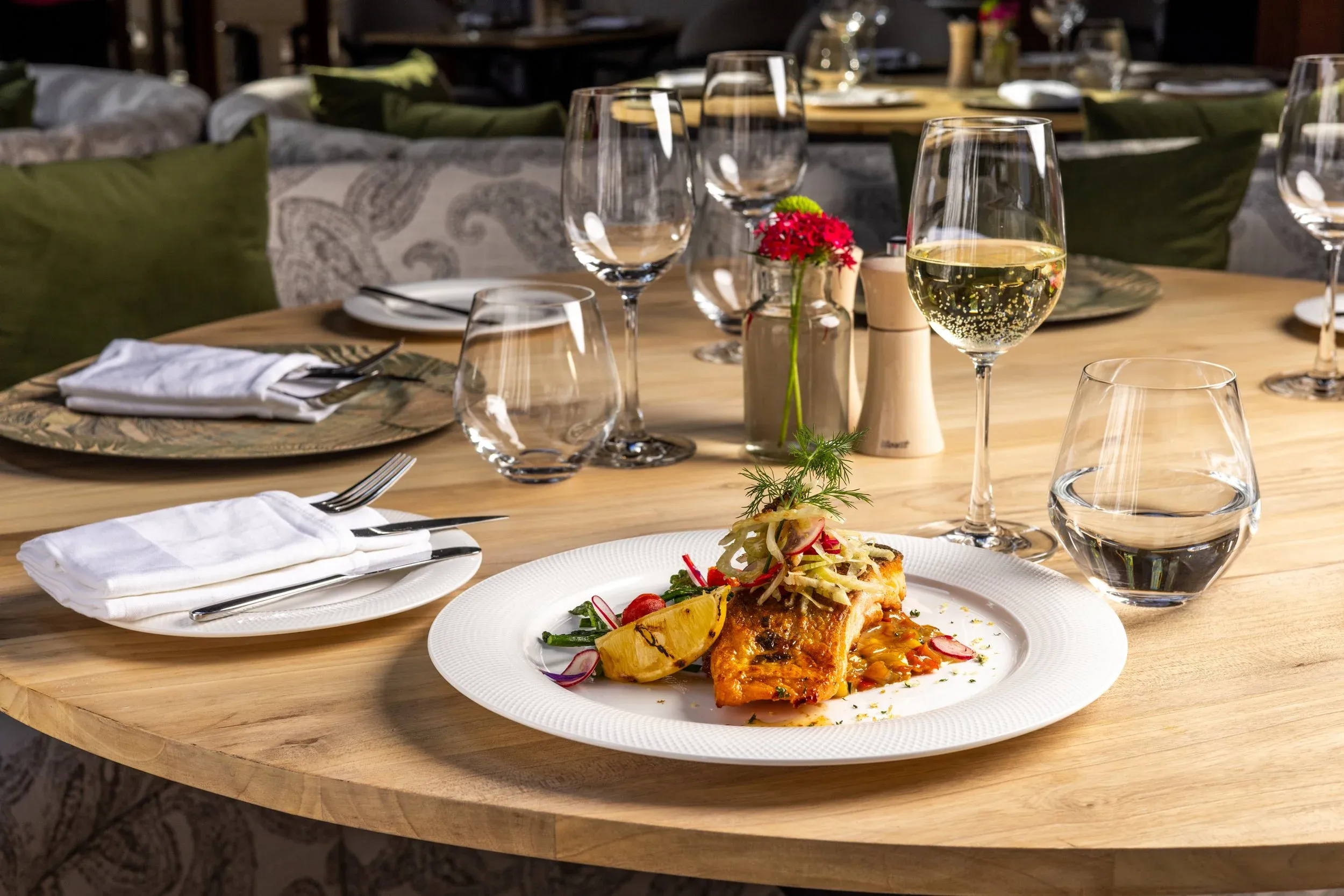 Grilled fish with vegetables on a round table laid for dinner