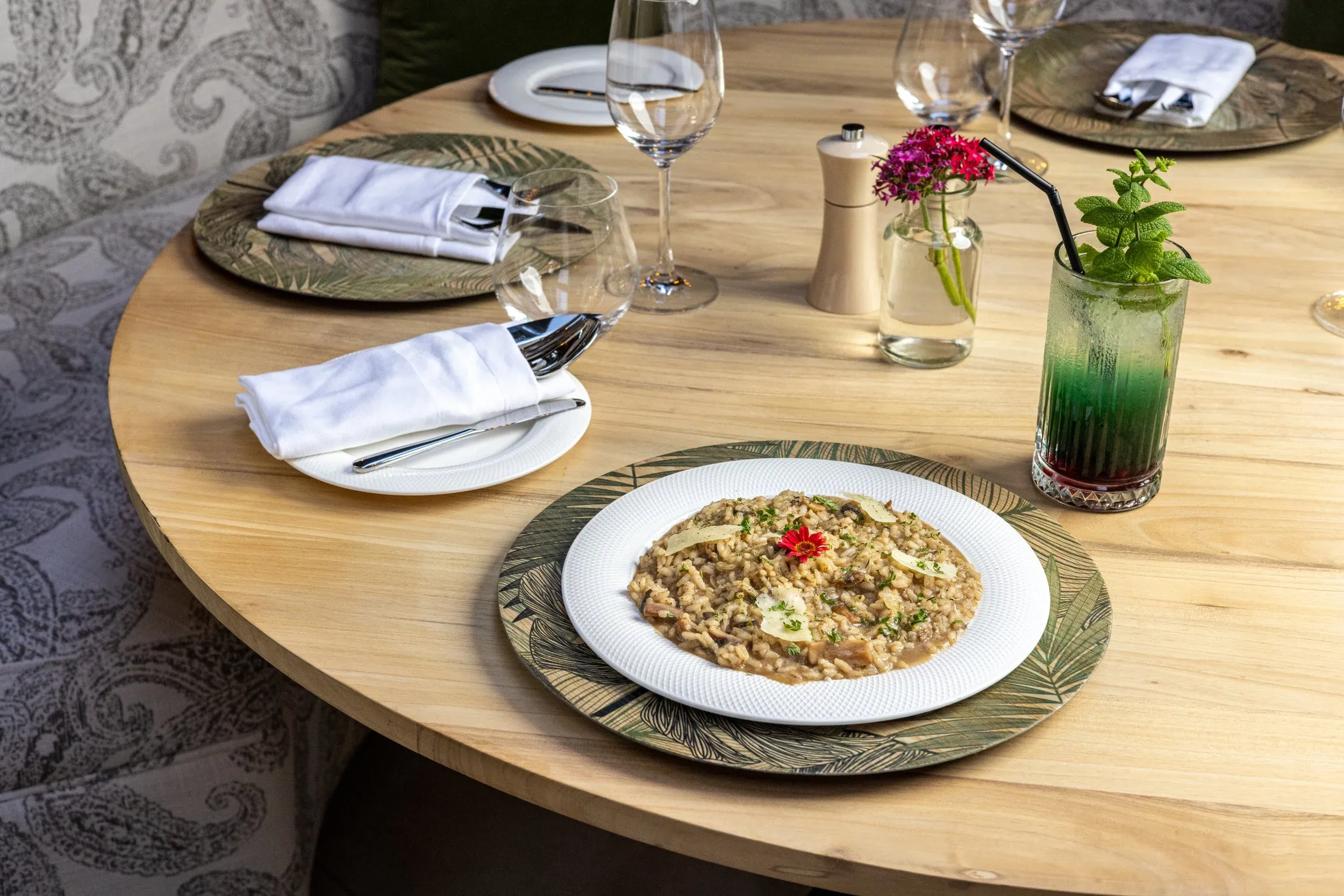 Risotto served on a patterned charger with a green mocktail