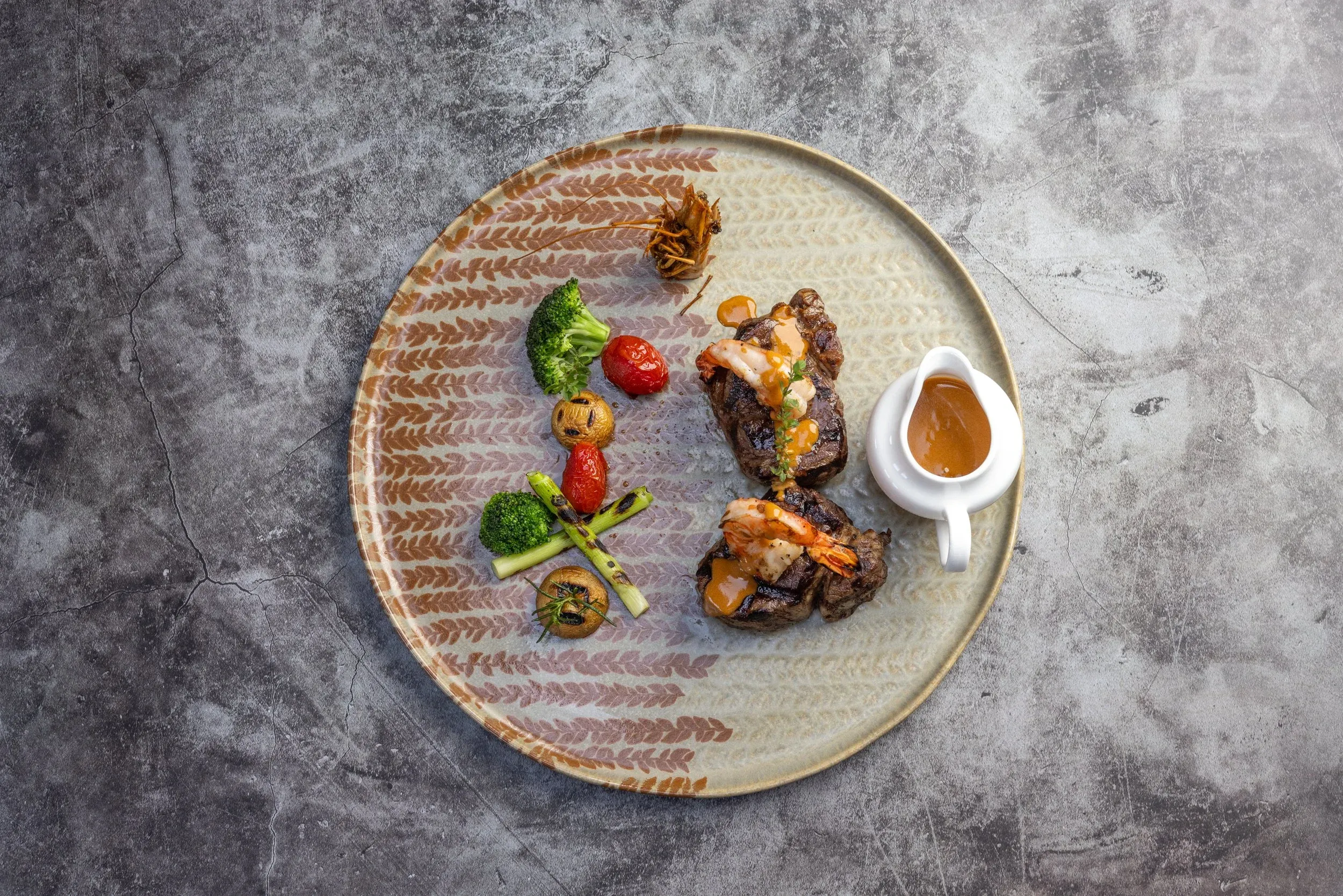 Overhead view of surf and turf with a jug of sauce