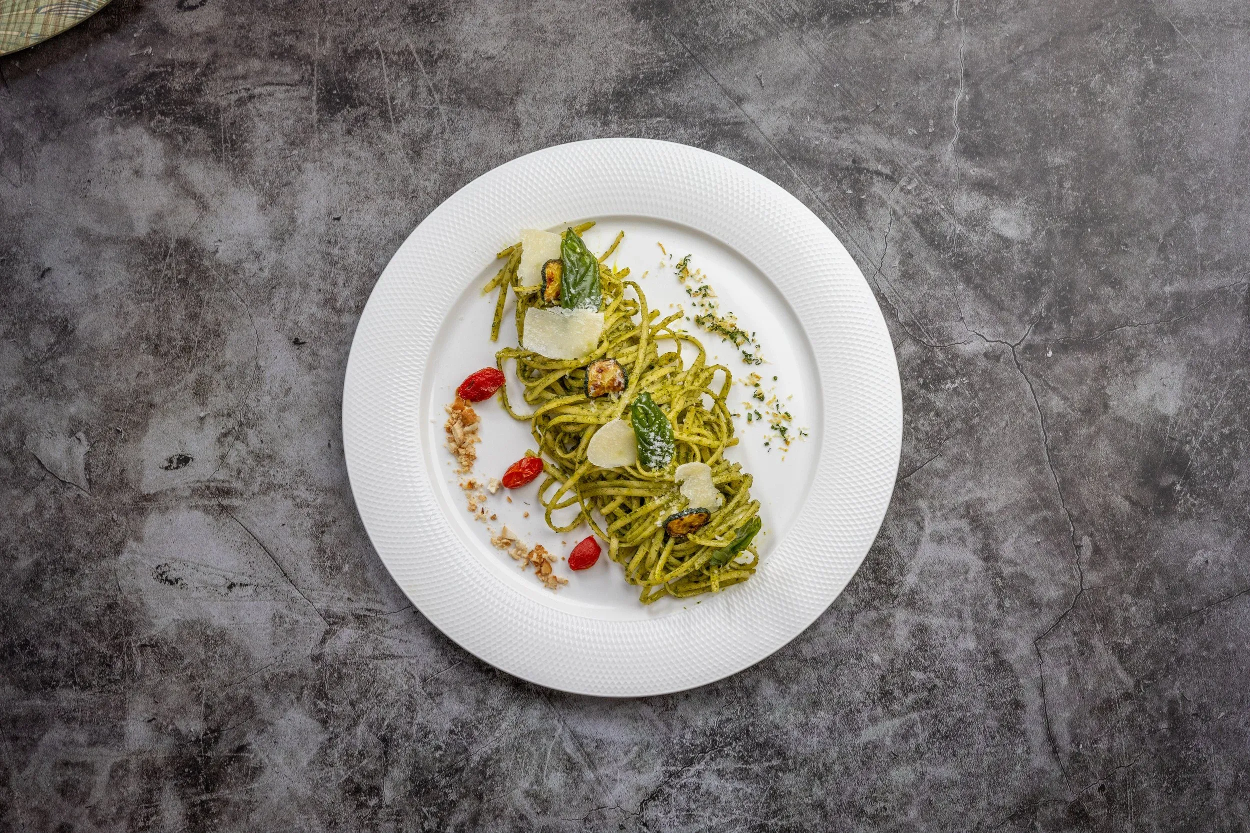 Overhead view of pesto pasta on a white plate